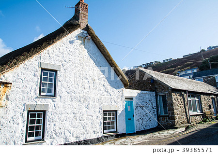 白く塗られ壁とかやぶき屋根のた石造りの家の写真素材