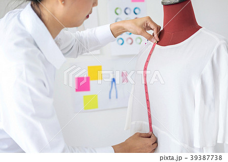 Young woman dressmaker or designer working as measuring for clot Young woman dressmaker or designer working as measuring for clot 39387738