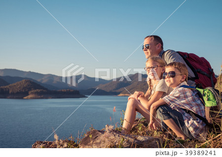 Happy family sitting near a lake at the day time. 39389241