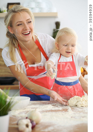 Little girl and her blonde mom in red aprons 39394939