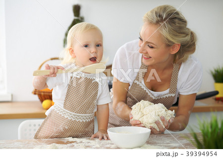 Little girl and her blonde mom in red aprons Little girl and her blonde mom in red aprons 39394954