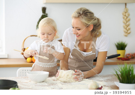 Little girl and her blonde mom in red aprons Little girl and her blonde mom in red aprons 39394955
