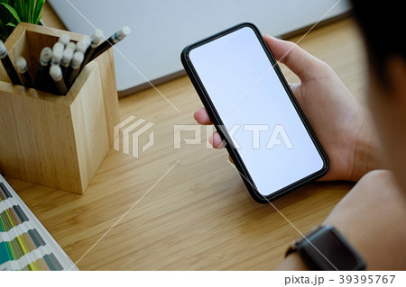 Blank screen mobile phone in hands on desk 39395767