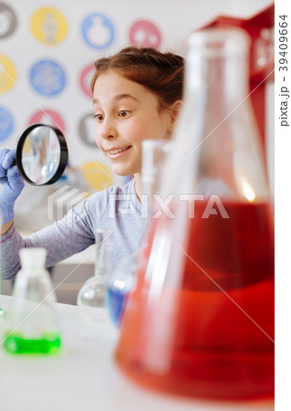 Upbeat teenage girl looking through magnifying Upbeat teenage girl looking through magnifying 39409664