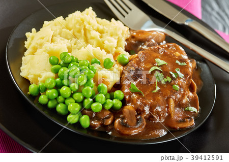 close-up of salisbury steaks with green peas 39412591
