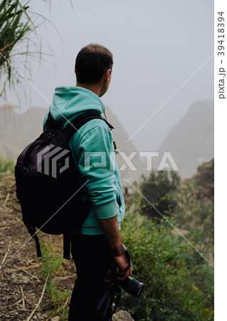 Traveler holding camera stand in front of rural 39418394