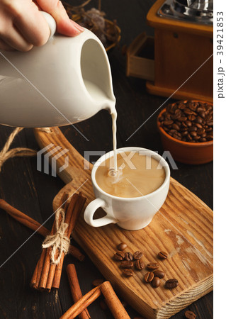 Woman pouring milk into black coffee on vintage 39421853