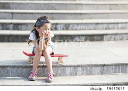 スケートボードに座る女の子の写真素材
