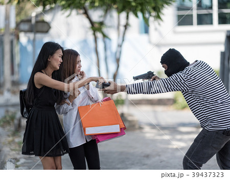 Masked robber is robbing at two shopping women. Masked robber is robbing at two shopping women. 39437323