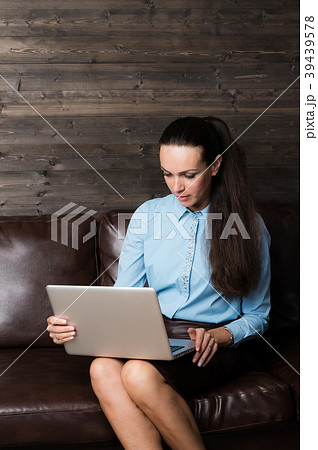 Happy brunette sitting on sofa in living room 39439578