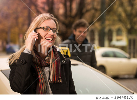 Young woman in front of taxi with phone Young woman in front of taxi with phone 39440170