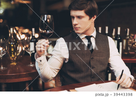Young confident sommelier makes notes in notebook 39443398