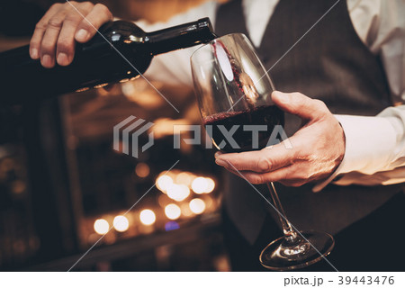 Elegant waiter pours red wine from bottle Elegant waiter pours red wine from bottle 39443476