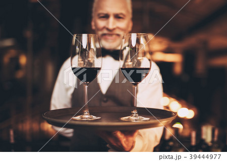 Sommelier with bow tie holds tray with glasses 39444977