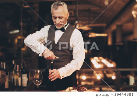 Elegant experienced sommelier uncorking bottle  39444981