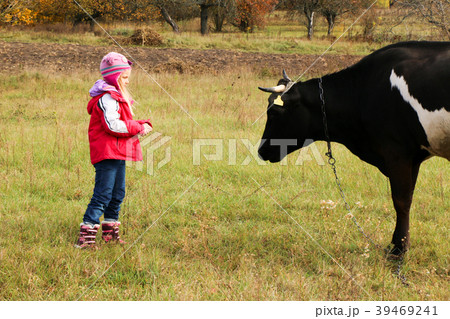 Beautiful little girl stands on meadow near black 39469241
