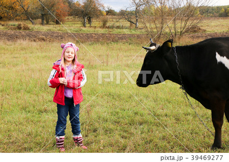 Beautiful little girl stands on meadow near black 39469277