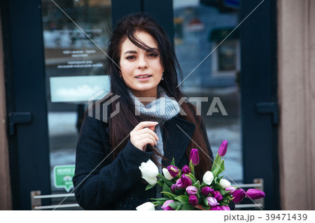 Happy woman holding spring flowers outdoor in city 39471439