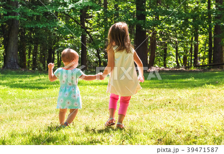 Two young sisters holding hands outside 39471587