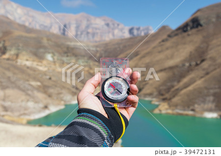 A man's hand holds a pocket magnetic compass for 39472131