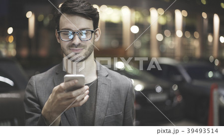 A smiling man is holding and looking at his A smiling man is holding and looking at his 39493514