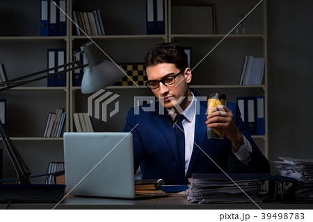 Employee working late and drinking strong coffee Employee working late and drinking strong coffee 39498783