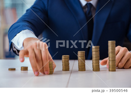 Businessman with stacks of coins in the office Businessman with stacks of coins in the office 39500546
