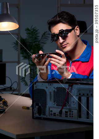 Computer specialist repairing PC late at night Computer specialist repairing PC late at night 39507355