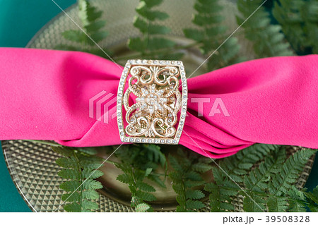 Pink napkin with a patterned clip. table setting 39508328
