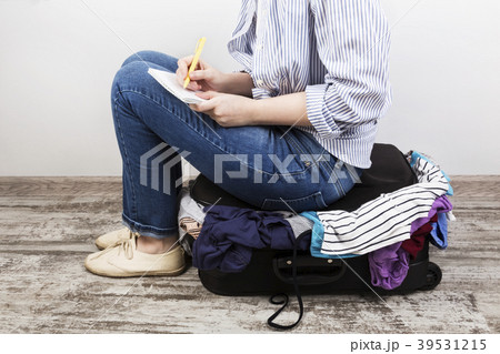 Young girl casually packs black suitcase 39531215