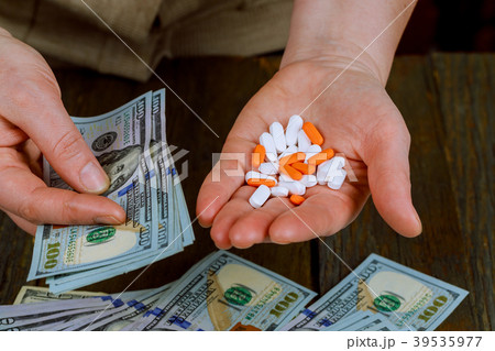 Woman's hand holding red pills on Dollars  39535977