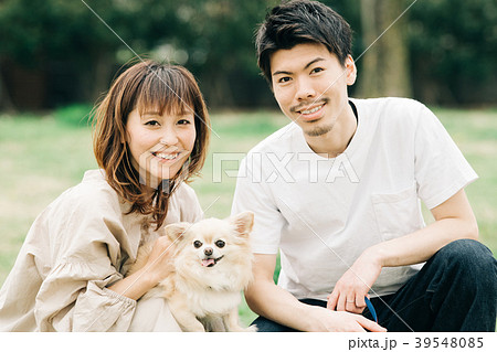 犬の散歩をする若い夫婦の写真素材