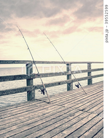 Several fishing rods against the wooden railing  39552599