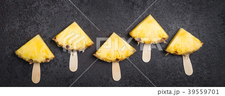 Ripe Pineapple slices on sticks on a black 39559701