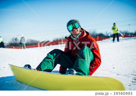Snowboarder in glasses sitting on snowy slope Snowboarder in glasses sitting on snowy slope 39560993