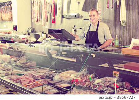 Male seller posing with wursts in butchery Male seller posing with wursts in butchery 39567727