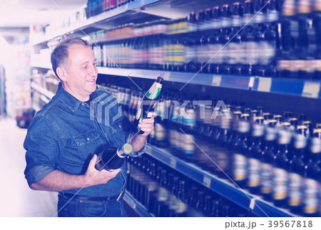 Glad pensioner selecting a beer at the store Glad pensioner selecting a beer at the store 39567818