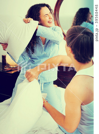 Happy young couple fighting on pillows in bed Happy young couple fighting on pillows in bed 39568448
