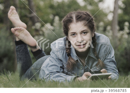 young girl using digital tablet while lying in green spring garden 39568785