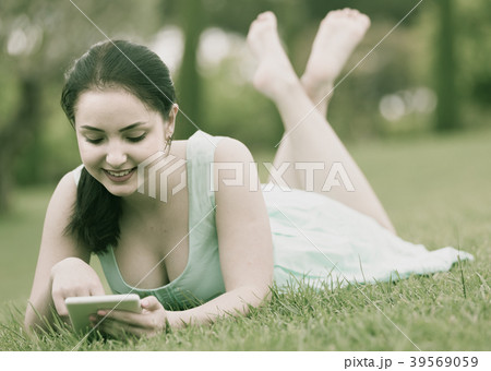young girl using digital tablet while lying in green spring garden young girl using digital tablet while lying in green spring garden 39569059