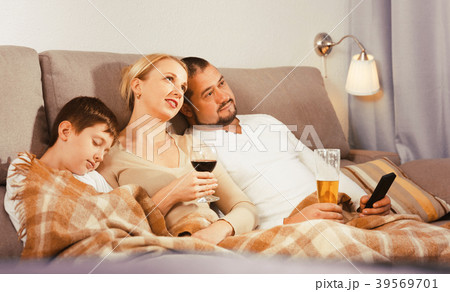 Happy family with sleeping son watching tv 39569701