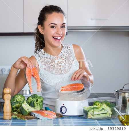Woman steaming salmon and vegetables. Woman steaming salmon and vegetables. 39569819