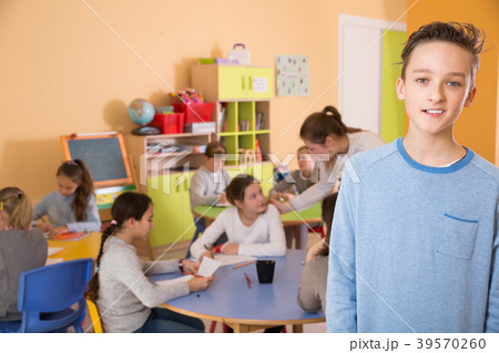 Smiling schoolboy standing, boys and girls in classroom Smiling schoolboy standing, boys and girls in classroom 39570260