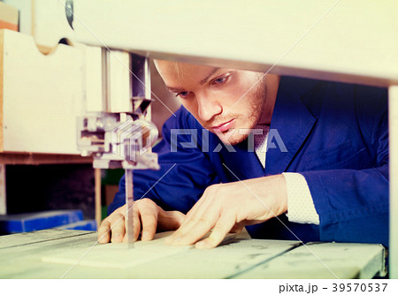guy using ribbon saw to cut plank at workshop 39570537