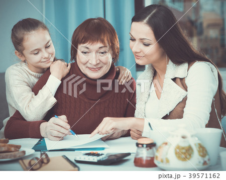 Smiling senior woman with family writing papers 39571162