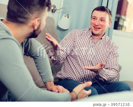 Cheerful man talking with friend on sofa 39571210