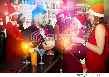 Man and two women in Santa hats celebrating at nightclub 39571736