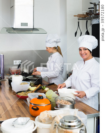 Two happy women chefs cooking food at kitchen Two happy women chefs cooking food at kitchen 39572180