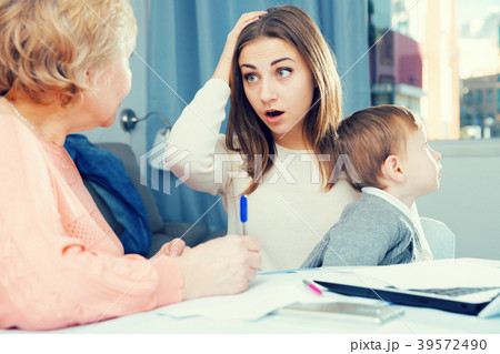 Puzzled aged woman is mastering technology near laptop with her daughter and grandson Puzzled aged woman is mastering technology near laptop with her daughter and grandson 39572490