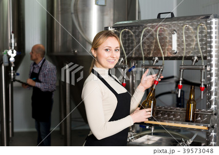 Smiling female brewery worker with bottling machinery 39573048